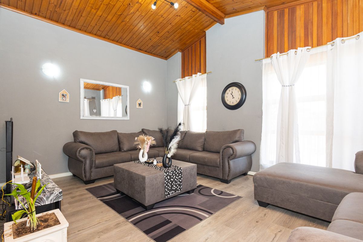 Spacious living room featuring a high vaulted timber ceiling, laminate flooring, and warm timber wall accents, creating a cozy and inviting atmosphere.