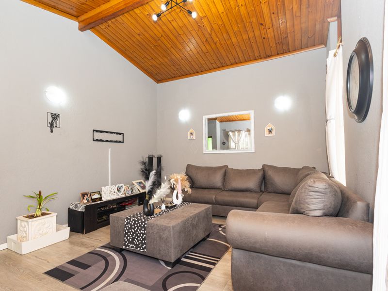 A comfortable living room featuring a high exposed timber raked ceiling and durable laminate flooring, providing a warm and inviting atmosphere.