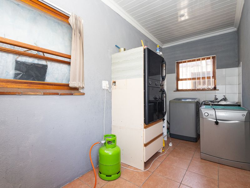 A functional laundry area featuring tiled flooring, built-in cabinetry, and plumbing connections for appliances, offering a practical space for utility tasks.