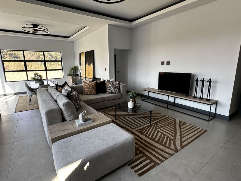 A spacious open-plan living and dining area featuring modern recessed ceilings, large format floor tiles, and expansive windows that provide ample natural light.