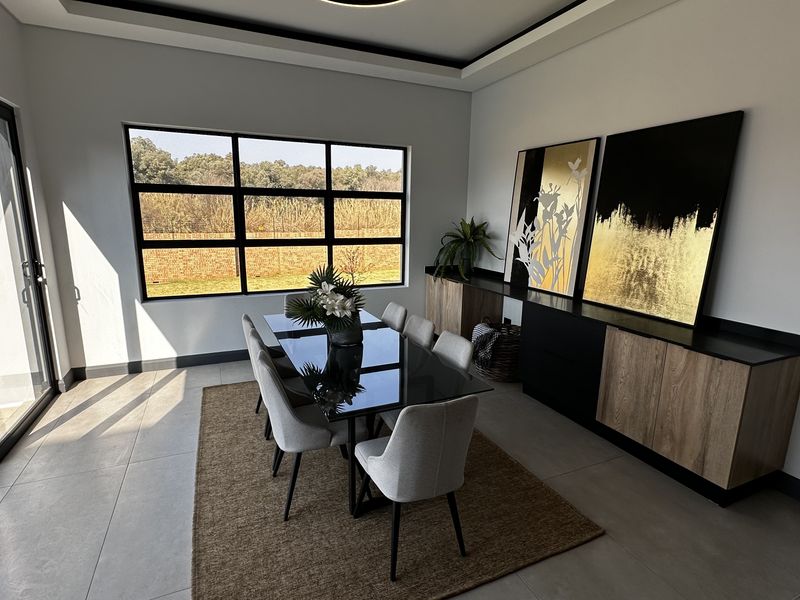 Modern dining room featuring large format floor tiles, built-in cabinetry, and expansive windows providing natural light and garden views.