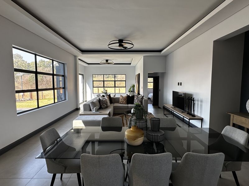 Spacious open-plan living and dining area featuring large grid-style windows, recessed ceilings, and modern tiled flooring, offering a bright and contemporary atmosphere.