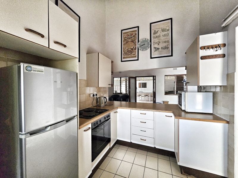 A functional kitchen featuring built-in cabinetry, laminate countertops, an electric hob, and an oven, with tiled flooring and a tiled backsplash.