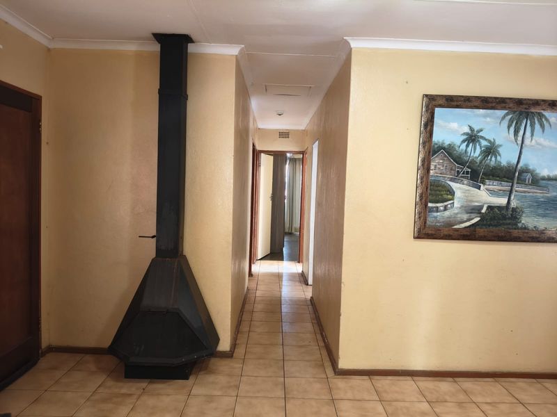 A tiled hallway featuring a black freestanding fireplace and access to adjacent rooms, finished with neutral wall paint and coved ceilings.