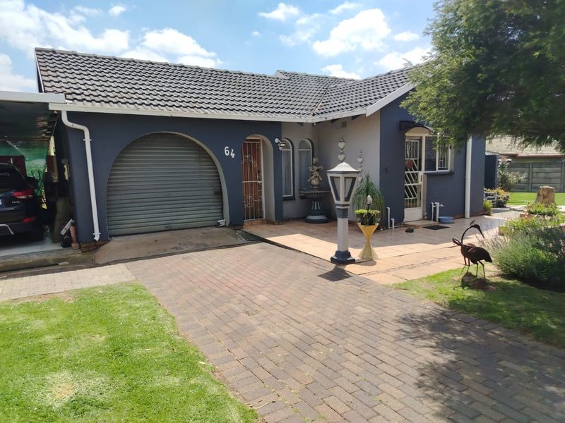 Front elevation of a single-story house featuring a paved driveway, arched garage entrance, and tiled roof.