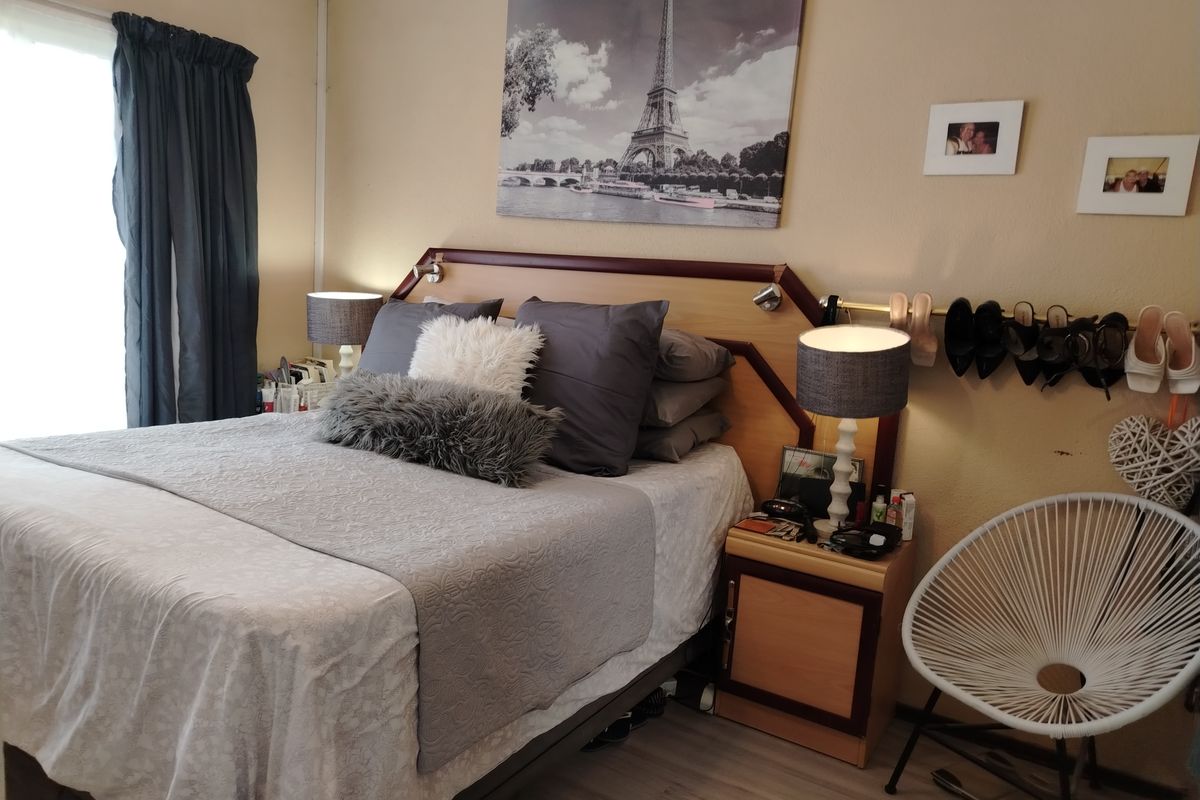 A cozy bedroom featuring laminate flooring and a built-in headboard with integrated lighting.