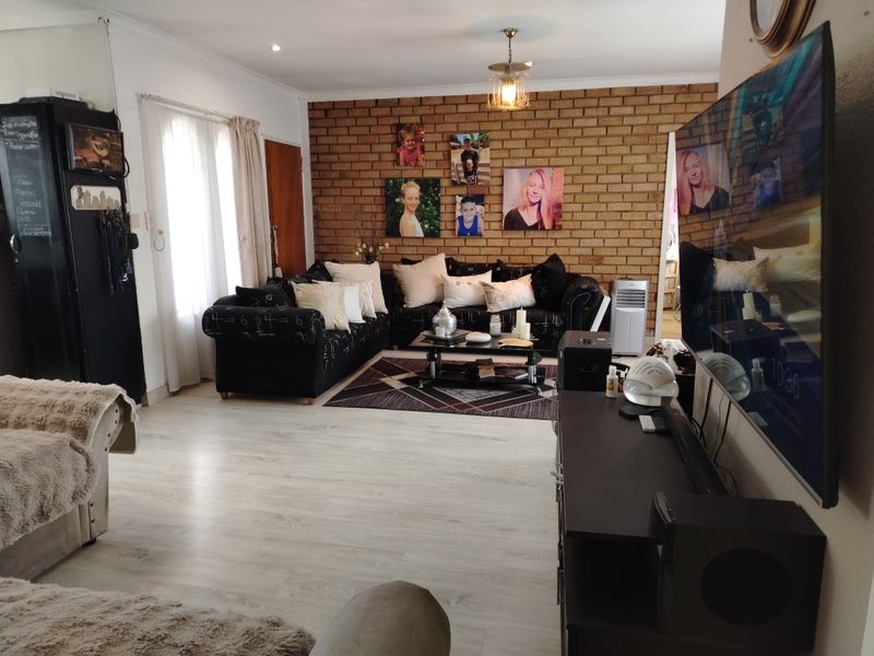 Spacious living room featuring a prominent exposed brick feature wall, light-toned laminate flooring, and modern recessed lighting.