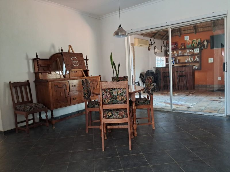 Dining area featuring dark floor tiles and a large sliding glass door providing access to an adjacent bar and entertainment space.