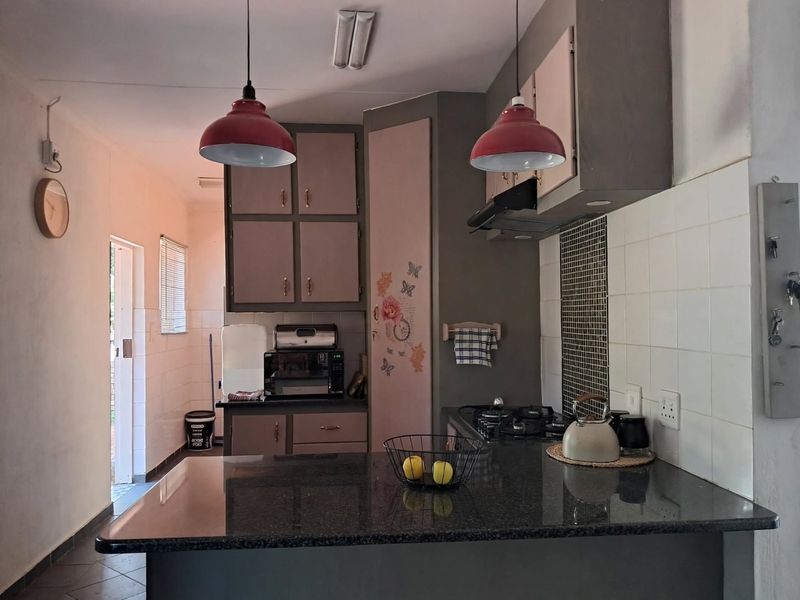 A functional kitchen featuring granite countertops, built-in cabinetry, a gas hob with extractor fan, and tiled backsplash, offering a practical layout for daily use.
