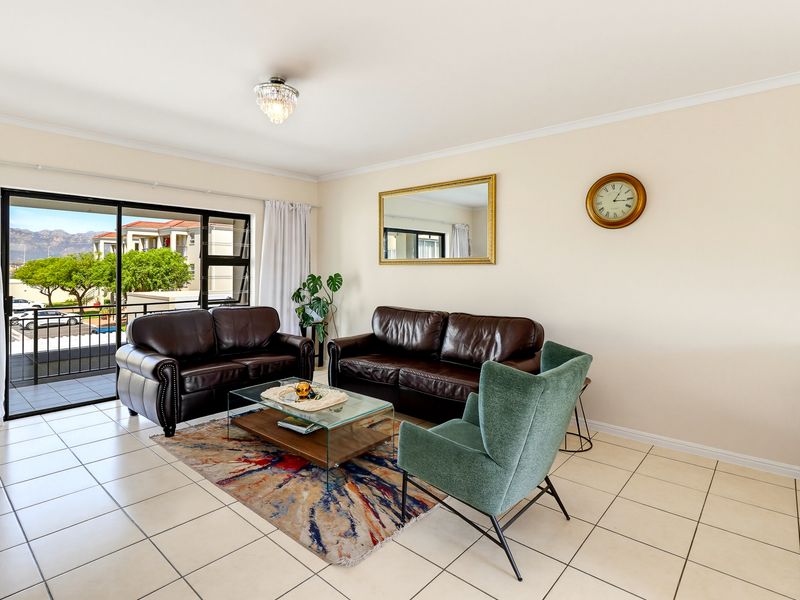 A bright and spacious living room featuring neutral tiled flooring and a large sliding glass door that opens onto a private balcony.