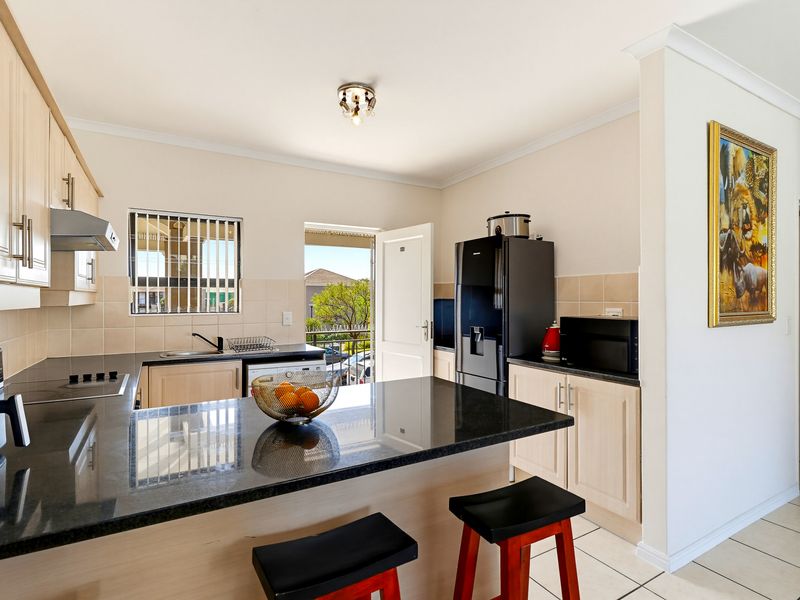 A functional kitchen featuring light wood cabinetry, dark granite countertops, ceramic tile backsplash, and direct access to an outdoor balcony area.