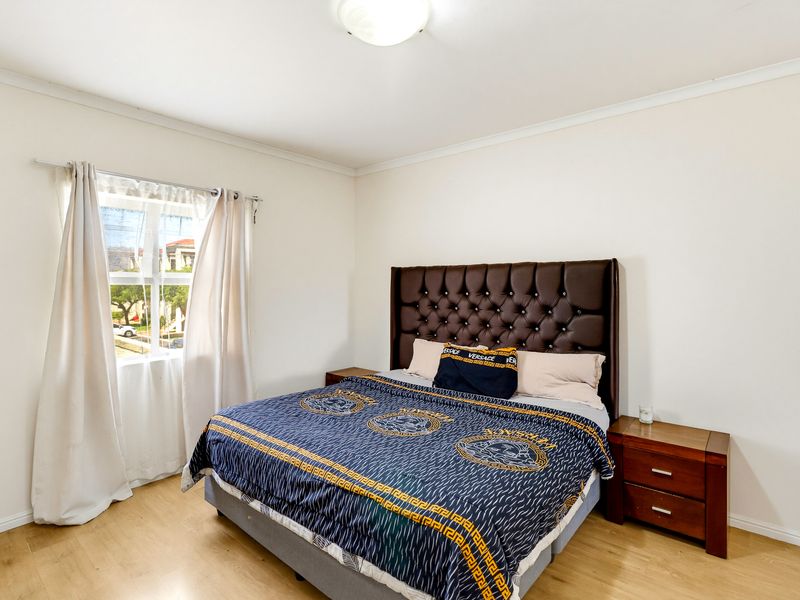 A well-lit bedroom featuring light-toned laminate flooring and a neutral color palette, providing a clean and comfortable living space.