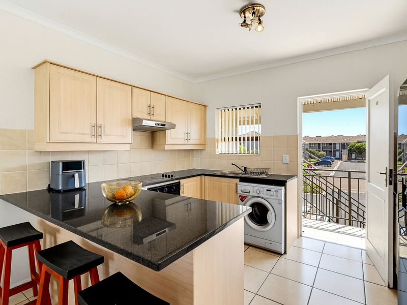 Functional kitchen featuring light wood cabinetry, granite countertops, built-in appliances, and direct access to an outdoor balcony area.