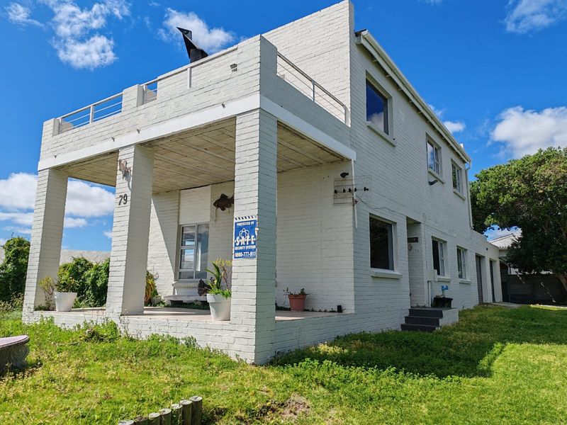Two-story painted brick house featuring a covered front patio and an upper-level balcony with metal railings.
