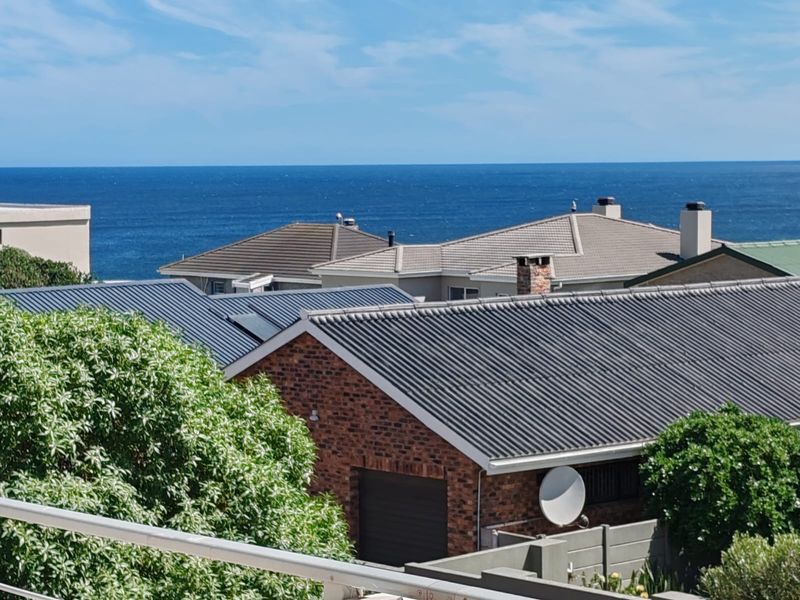 An elevated view overlooking neighbouring residential rooftops with a clear outlook towards the ocean horizon.