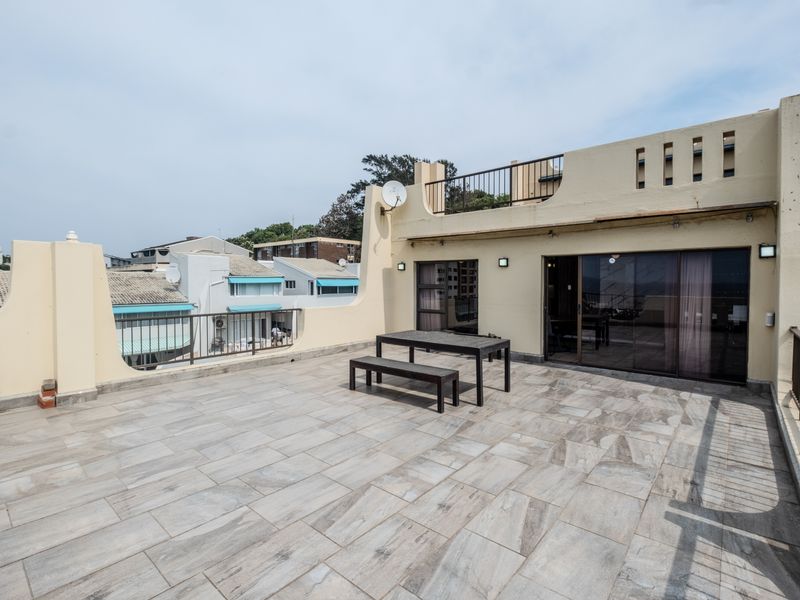 Spacious rooftop balcony featuring tiled flooring, metal railings, and sliding glass door access to the interior living area.