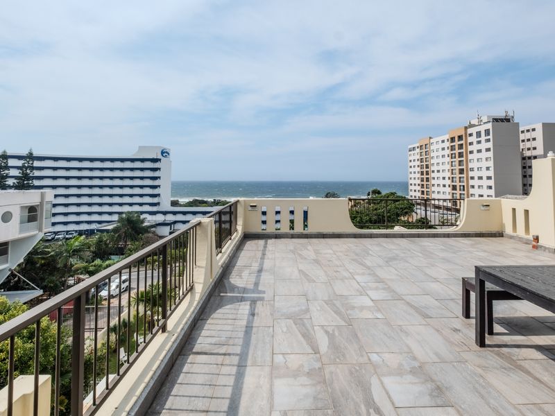 Spacious open-air balcony featuring tiled flooring, metal railings, and expansive ocean views, providing an ideal setting for outdoor relaxation.