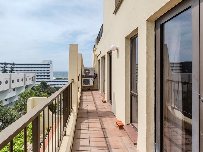 A spacious balcony featuring tiled flooring, metal railings, and direct access to the apartment, offering an outdoor area with views of the surrounding neighborhood.