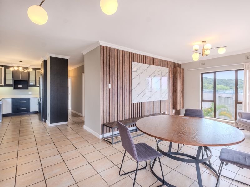 Spacious open-plan living and dining area featuring modern timber wall paneling, tiled floors, and a well-appointed kitchen with contemporary cabinetry and integrated appliances.