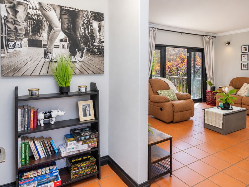 A view from a hallway into a living room featuring terracotta floor tiles and sliding glass doors leading to an outdoor area.