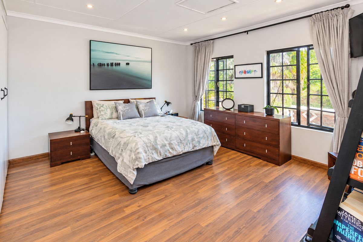 A well-maintained bedroom featuring laminate flooring, recessed downlighting, and large windows that provide natural light.