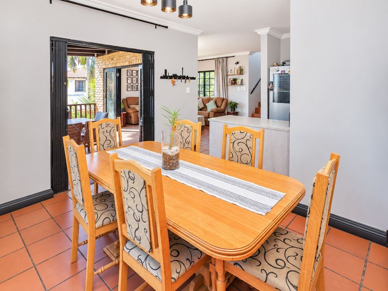 Open-plan dining area featuring terracotta floor tiles, crown molding, and seamless access to an outdoor patio through bi-fold doors.