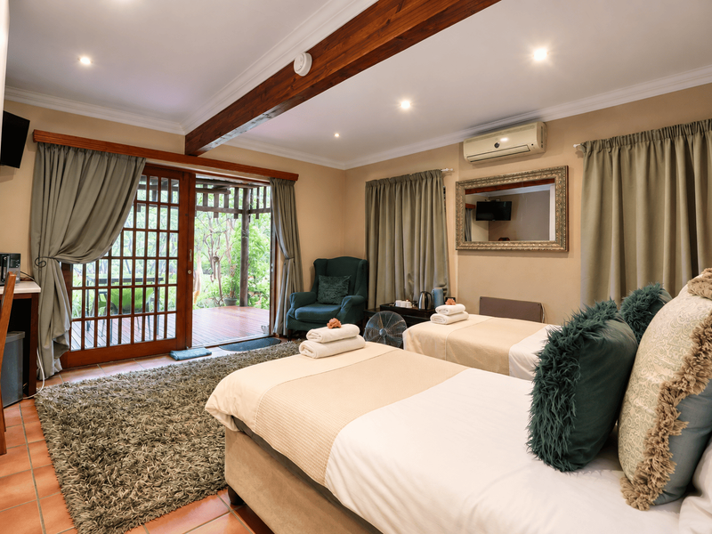 A well-maintained bedroom featuring exposed timber ceiling beams, tiled flooring, and sliding glass doors providing direct access to an outdoor patio area.