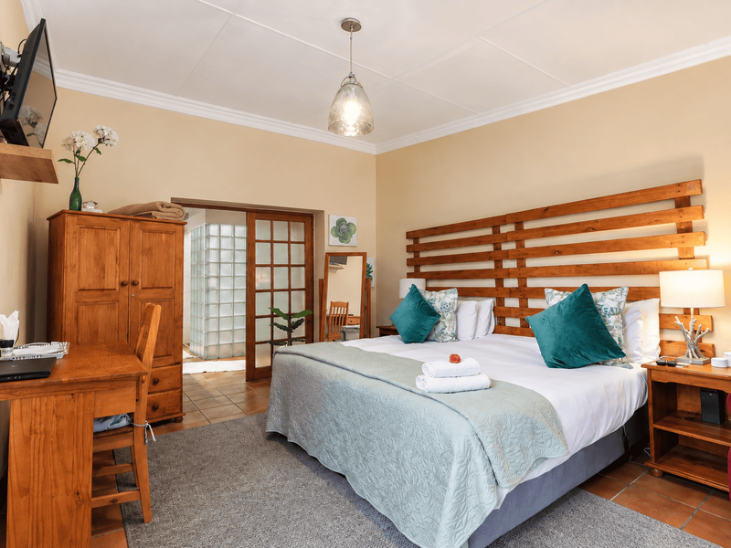 A well-maintained bedroom featuring a timber headboard, coved ceilings, and a glass block partition leading to an adjoining space with tiled flooring.