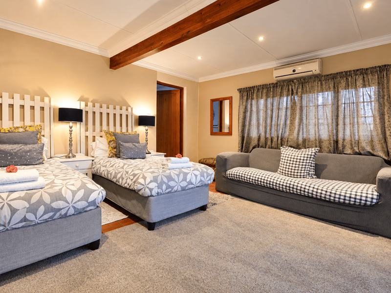 Spacious bedroom featuring an exposed timber ceiling beam, recessed lighting, and a wall-mounted air conditioning unit.