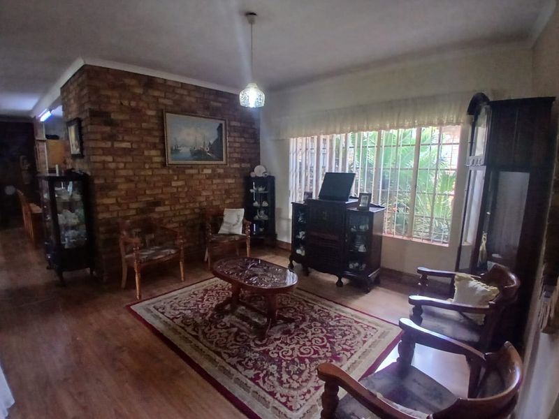 A cozy living room featuring an exposed brick accent wall, laminate flooring, and large windows that provide natural light.