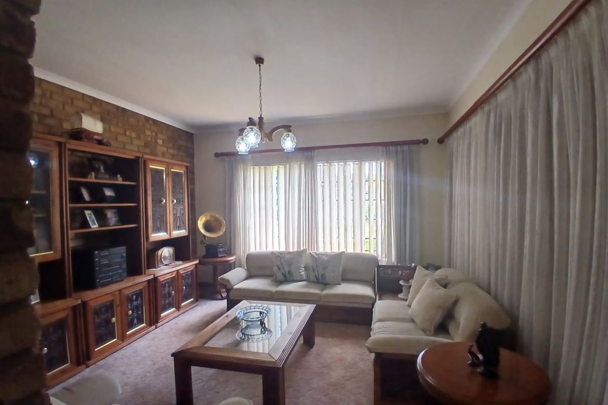 A living room featuring an exposed brick wall, built-in wooden cabinetry, and large windows with curtain rails.