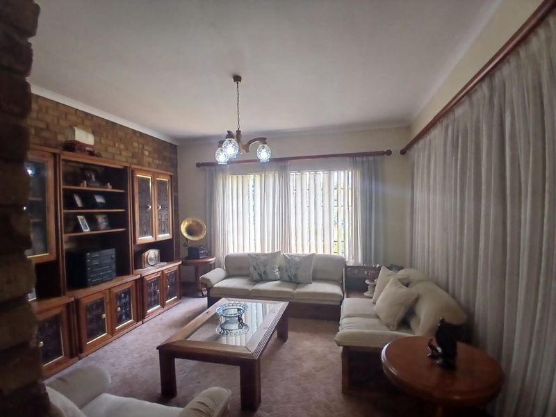 A living room featuring an exposed brick wall, built-in wooden cabinetry, and large windows with curtain rails.