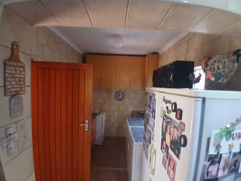A functional scullery area featuring built-in cabinetry, tiled wall finishes, and tiled flooring, providing additional utility space adjacent to the main kitchen.