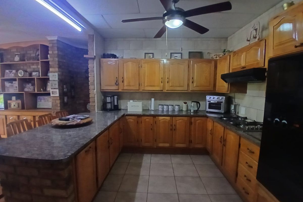 Spacious kitchen featuring traditional wooden cabinetry, granite countertops, a brick breakfast bar, and integrated appliances, offering a functional layout with ample storage space.