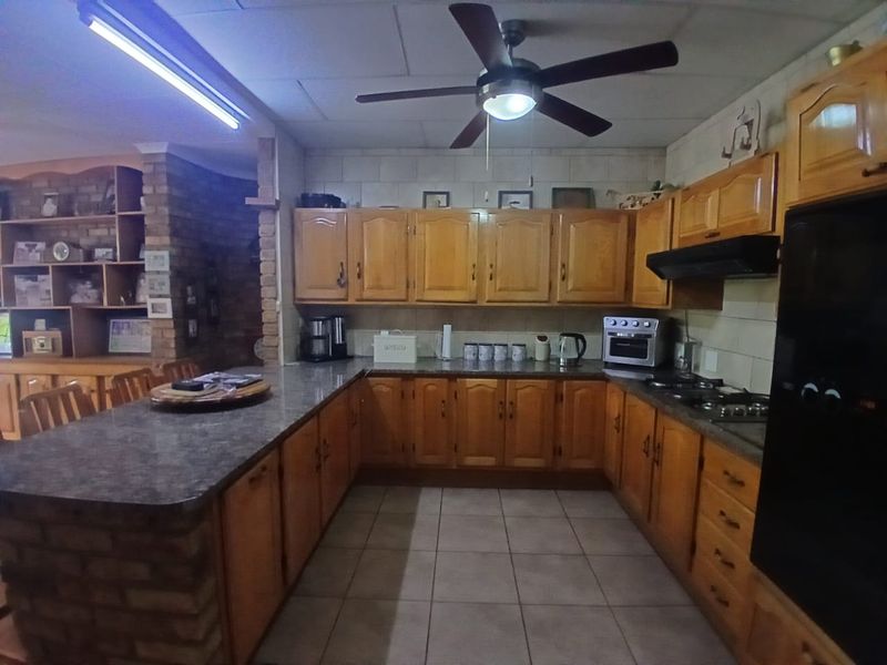 Spacious kitchen featuring traditional wooden cabinetry, granite countertops, a brick breakfast bar, and integrated appliances, offering a functional layout with ample storage space.