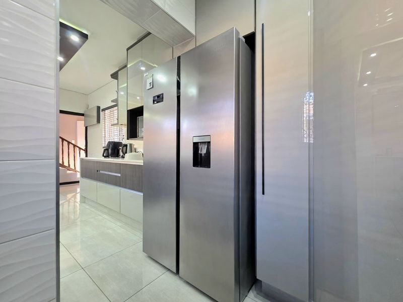 Modern kitchen featuring high-gloss cabinetry, integrated appliances, and sleek tiled flooring with recessed lighting.