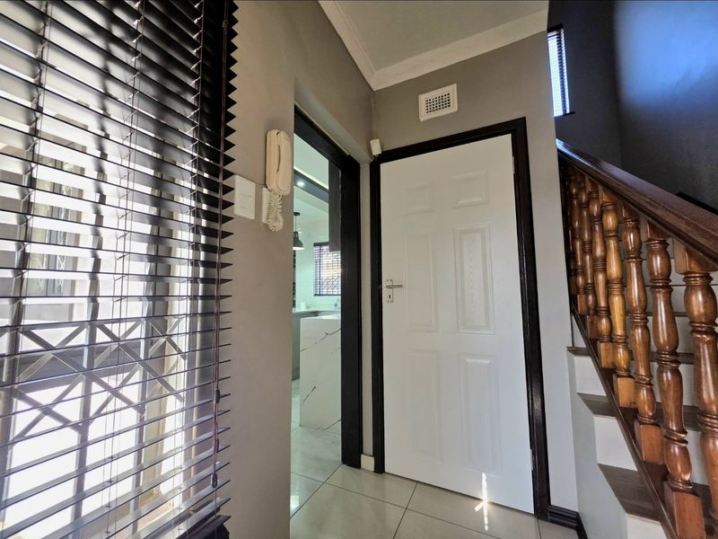 A bright hallway featuring tiled flooring, a wooden staircase with a traditional balustrade, and access to adjacent living spaces.