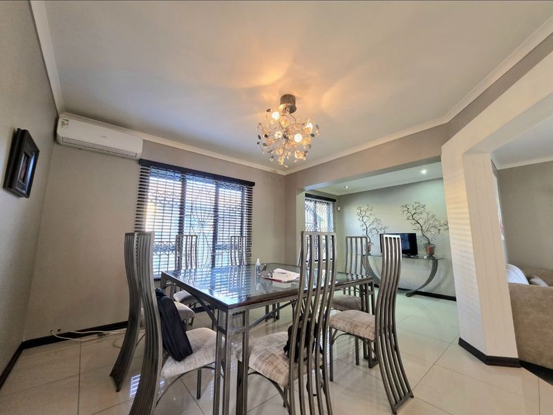 A well-maintained dining area featuring tiled flooring, modern recessed lighting, and an integrated air conditioning unit, flowing into an adjacent living space.