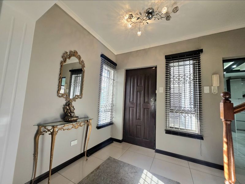 A bright and welcoming entrance hall featuring tiled flooring, a solid timber front door, security-fitted windows, and an integrated intercom system.