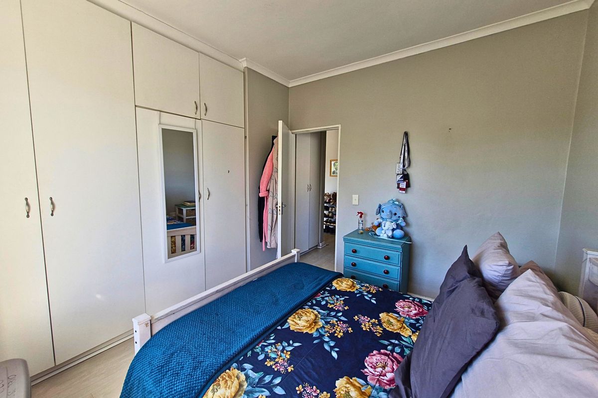 A bedroom featuring built-in cupboards with a mirrored panel, laminate flooring, and cove cornice detailing.