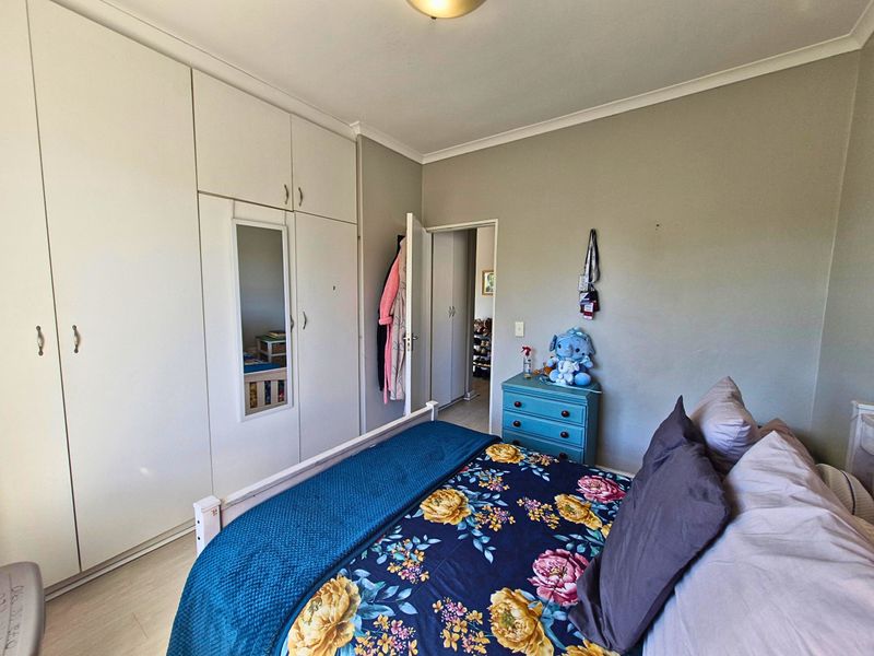 A bedroom featuring built-in cupboards with a mirrored panel, laminate flooring, and cove cornice detailing.