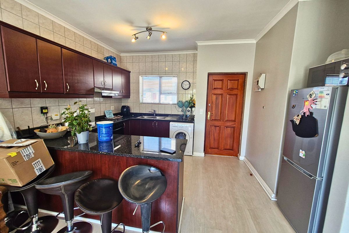 A functional kitchen featuring dark wood cabinetry, granite countertops, a tiled backsplash, and integrated laundry plumbing, offering a practical layout for daily use.
