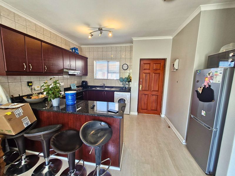 A functional kitchen featuring dark wood cabinetry, granite countertops, a tiled backsplash, and integrated laundry plumbing, offering a practical layout for daily use.
