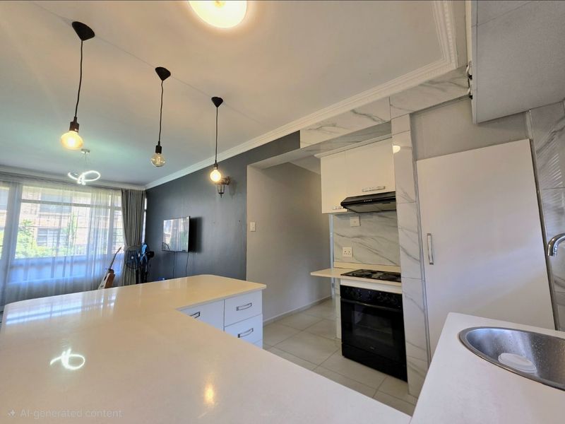 Modern open-plan kitchen and living area featuring a central island, sleek cabinetry, built-in appliances, and contemporary pendant lighting.