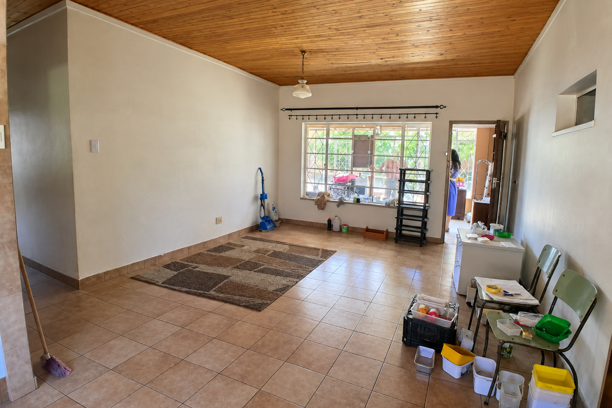 Spacious living area featuring a timber-clad ceiling, ceramic tiled flooring, and large windows with security bars, offering a blank canvas for interior design.