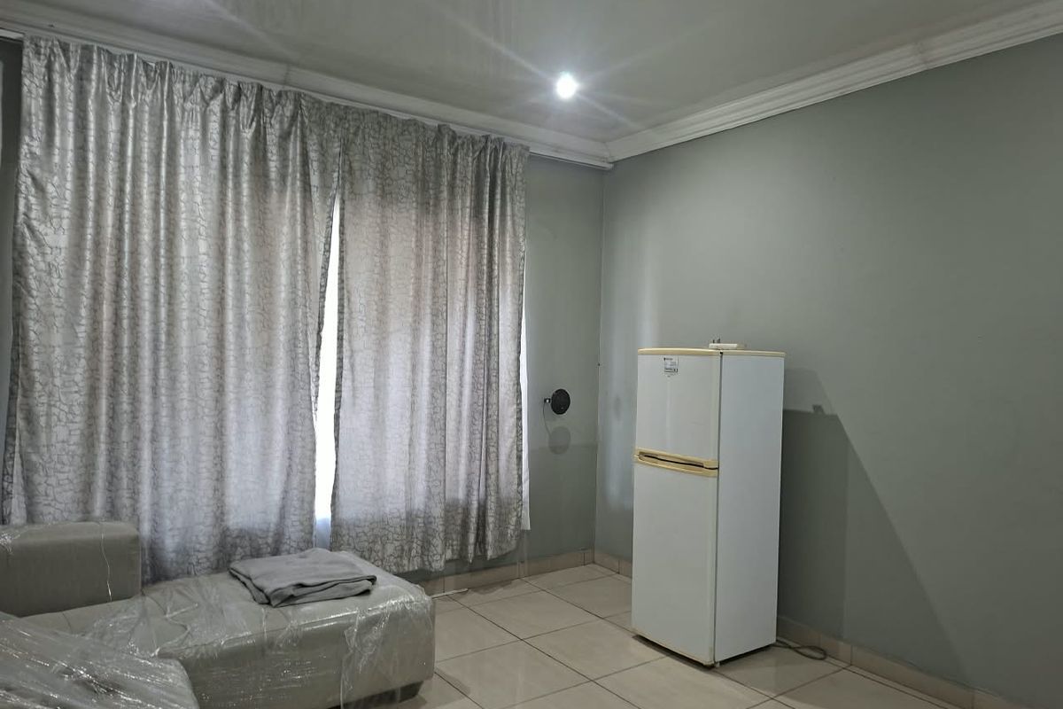 A living room featuring neutral wall paint, tiled flooring, and recessed ceiling lighting, providing a clean and functional space.