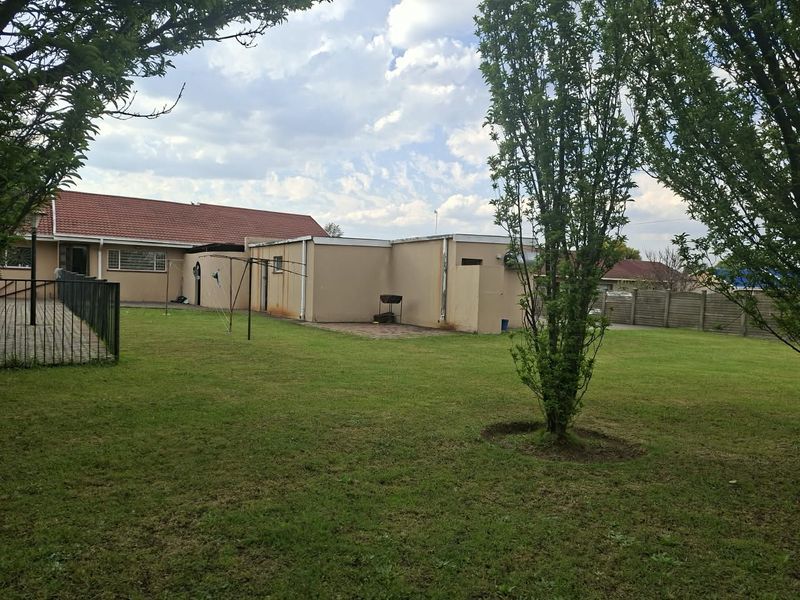 Spacious rear garden featuring a paved patio area, established lawn, and perimeter fencing, providing a private outdoor space for the property.