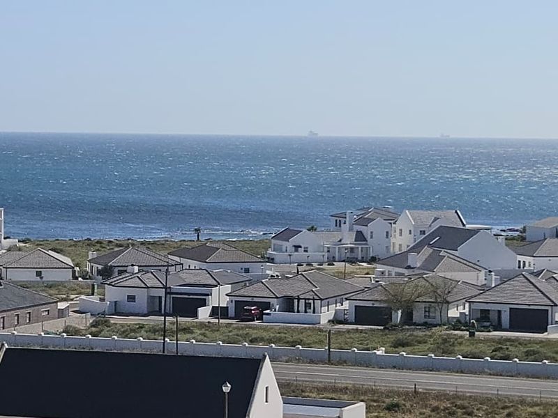 An elevated view overlooking a coastal residential estate with ocean vistas in the background.
