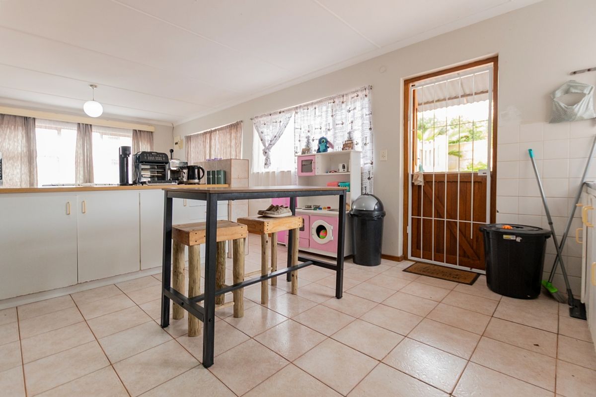 A functional kitchen area featuring tiled flooring, built-in cabinetry, and a wooden stable door with a security gate leading to the exterior.