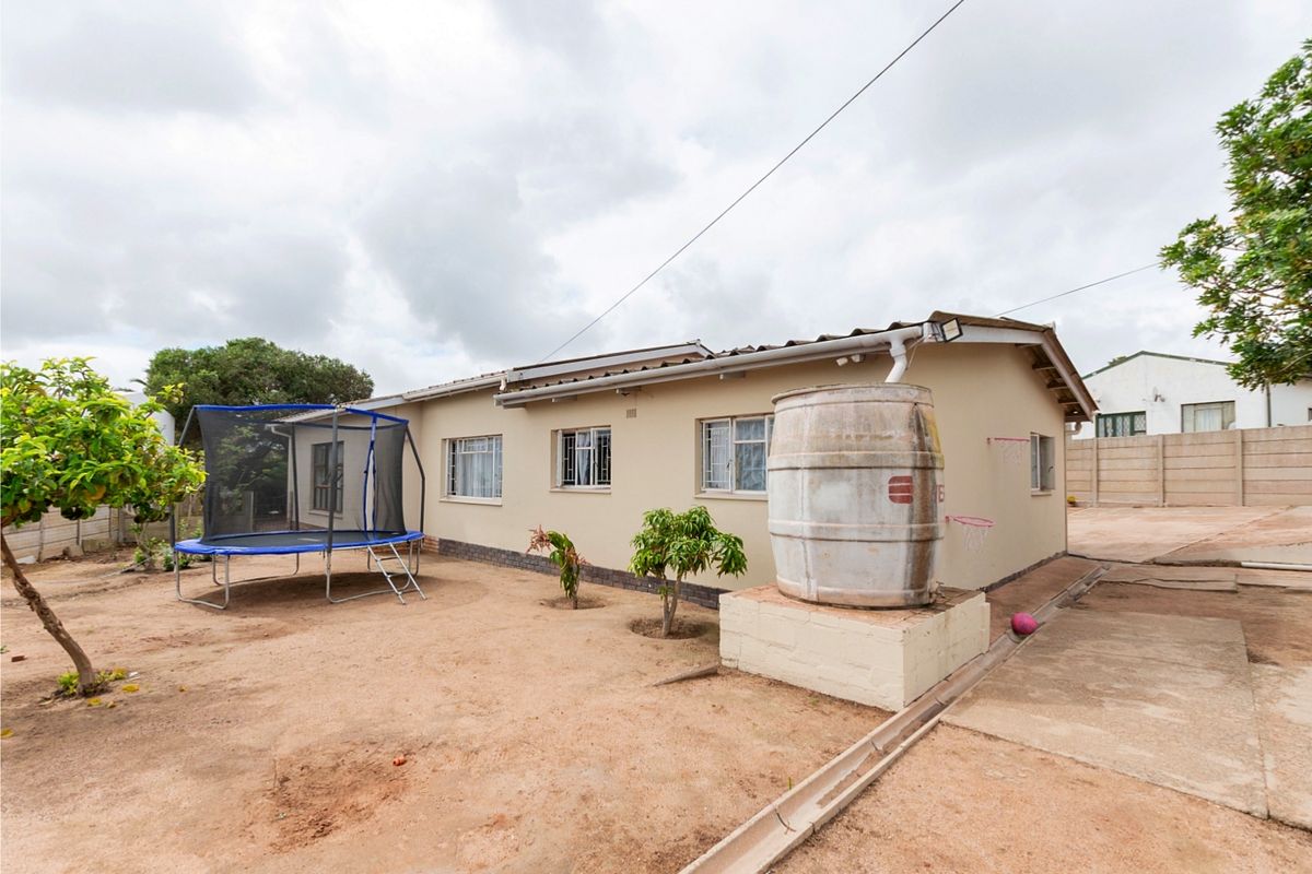 Rear exterior view of the house featuring a water storage tank on a concrete plinth, security bars on windows, and a precast boundary wall.